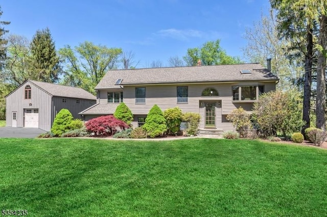 bi-level home featuring a front lawn, an outbuilding, and a detached garage