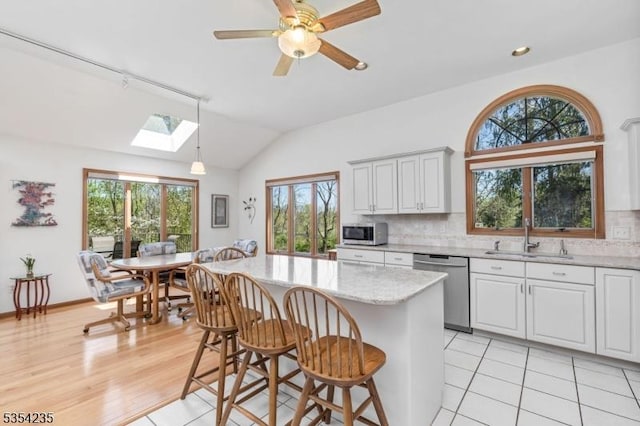 kitchen featuring appliances with stainless steel finishes, a sink, a breakfast bar area, a center island, and backsplash