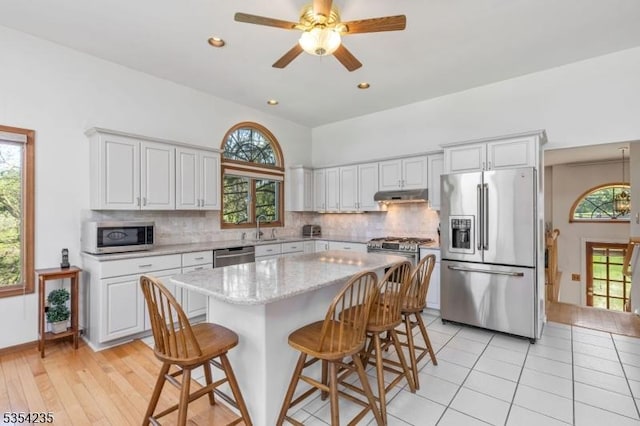 kitchen with a sink, appliances with stainless steel finishes, decorative backsplash, and under cabinet range hood