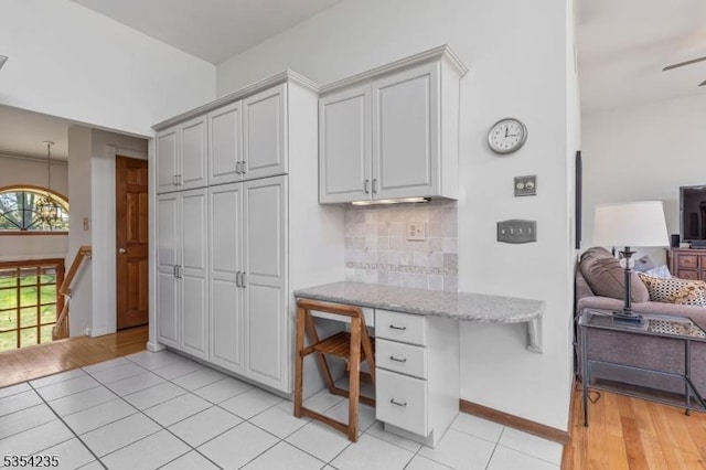 home office with light tile patterned floors, baseboards, and built in study area