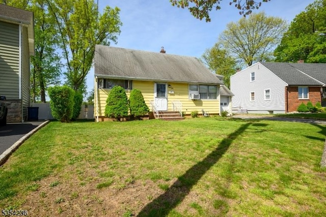 view of front of home featuring a chimney, cooling unit, and a front lawn