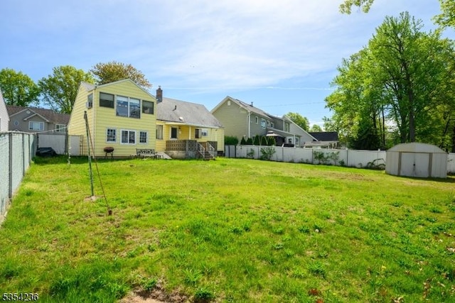 view of yard with an outdoor structure, a fenced backyard, and a storage shed