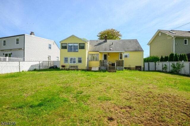 rear view of property with a fenced backyard and a yard