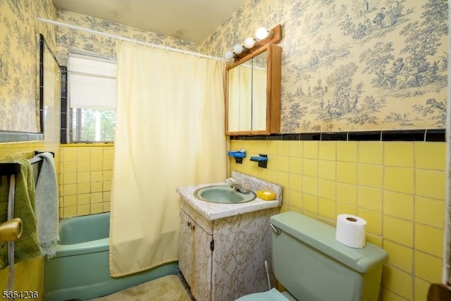 bathroom featuring tile walls, vanity, a wainscoted wall, toilet, and wallpapered walls