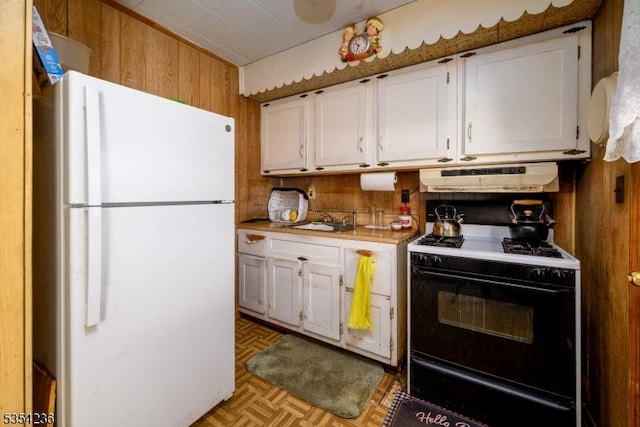 kitchen featuring gas stove, light countertops, freestanding refrigerator, under cabinet range hood, and white cabinetry