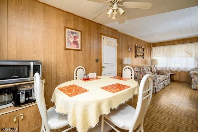 dining room featuring wooden walls and ceiling fan