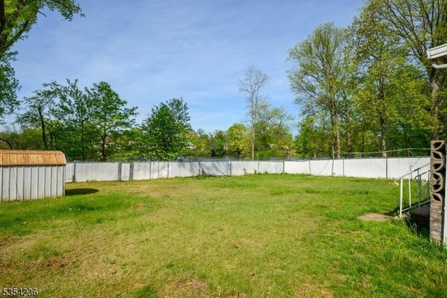 view of yard featuring a shed, an outbuilding, and fence