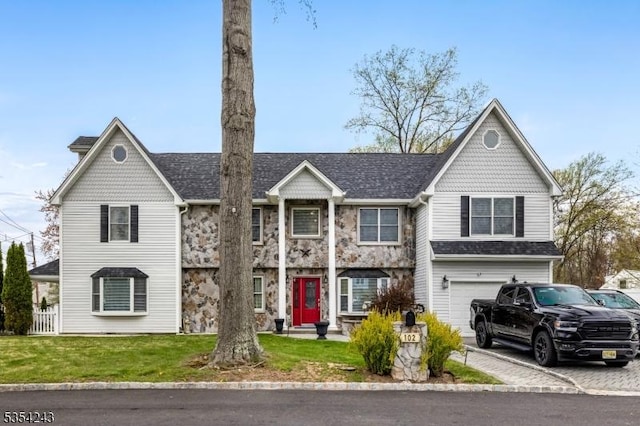 view of front facade with an attached garage, a shingled roof, and a front yard