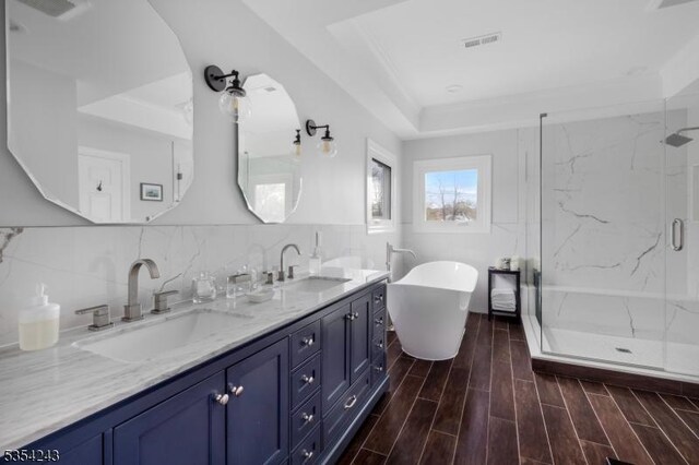 bathroom featuring visible vents, a sink, a marble finish shower, and double vanity