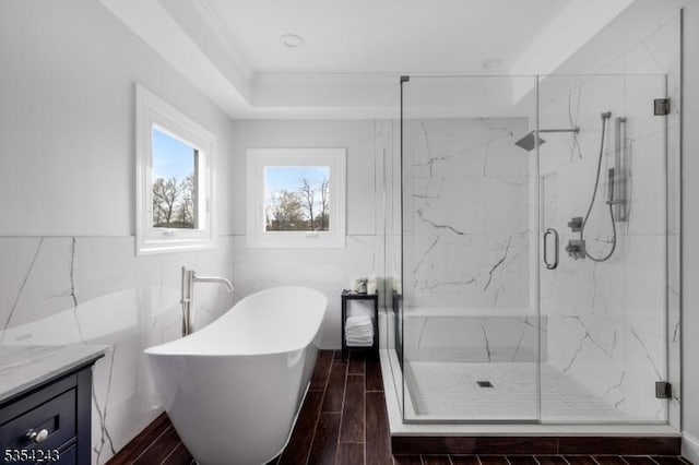 full bathroom with wood tiled floor, a freestanding bath, tile walls, vanity, and a marble finish shower
