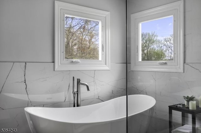 bathroom with a freestanding tub and tile walls
