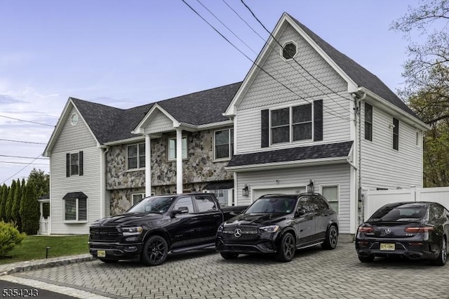 view of front facade featuring a garage, decorative driveway, fence, and a shingled roof