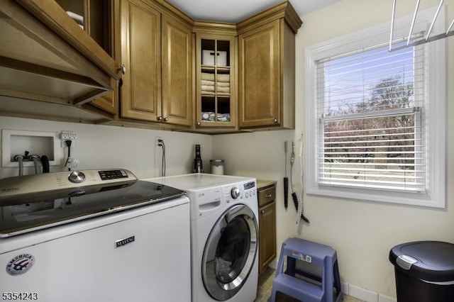clothes washing area featuring cabinet space and washer and clothes dryer