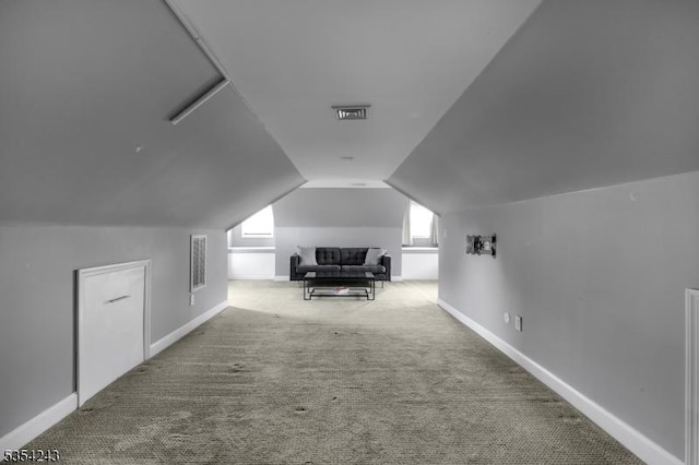 additional living space featuring carpet floors, baseboards, visible vents, and lofted ceiling