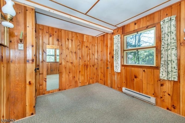 carpeted empty room with a baseboard radiator and wood walls