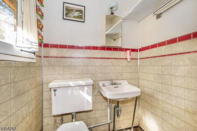 half bathroom with toilet, tile walls, and a sink