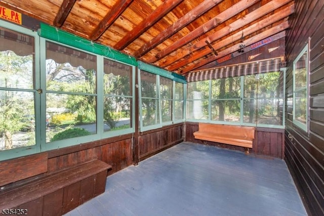 unfurnished sunroom featuring beamed ceiling and a wealth of natural light