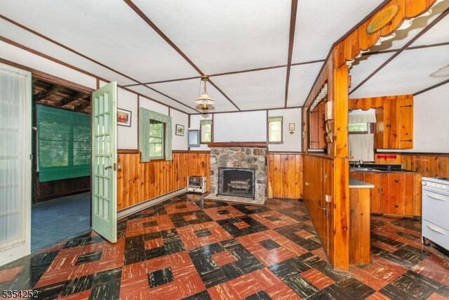 unfurnished living room featuring dark floors, wood walls, and a wainscoted wall