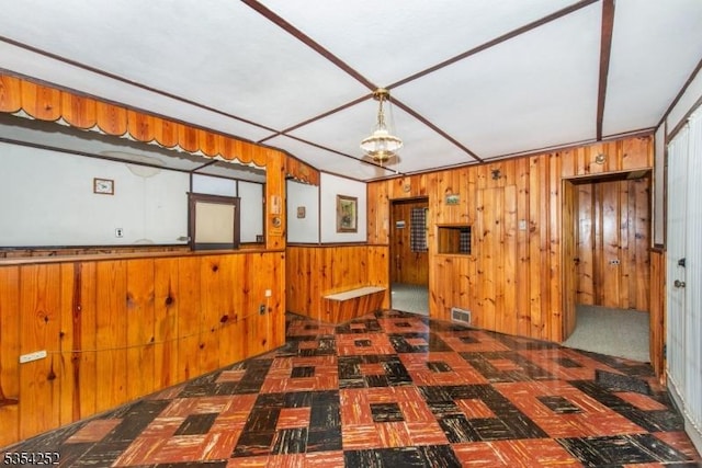 unfurnished room featuring wooden walls, tile patterned floors, and visible vents