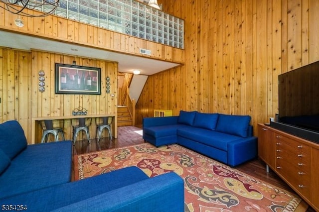 living room featuring wooden walls, stairway, wood finished floors, and visible vents