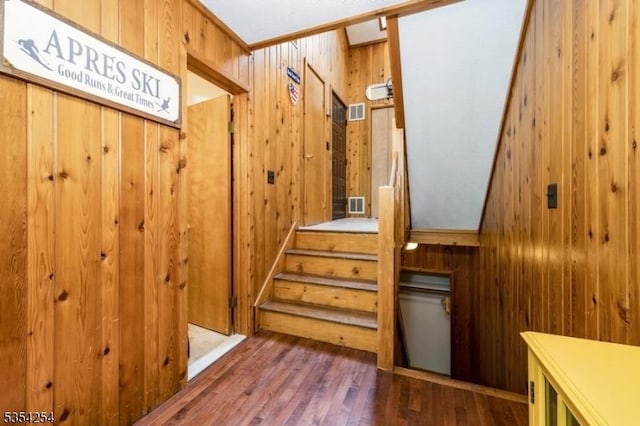 stairway featuring wood walls, wood finished floors, and visible vents