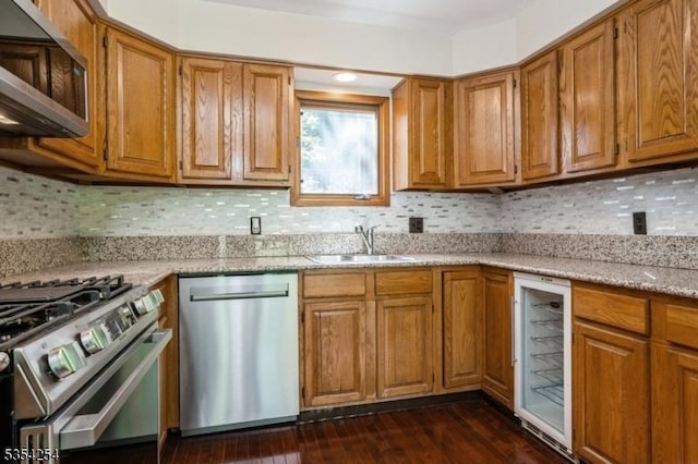 kitchen with a sink, appliances with stainless steel finishes, brown cabinets, and beverage cooler