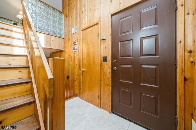 tiled entryway featuring wooden walls and stairway