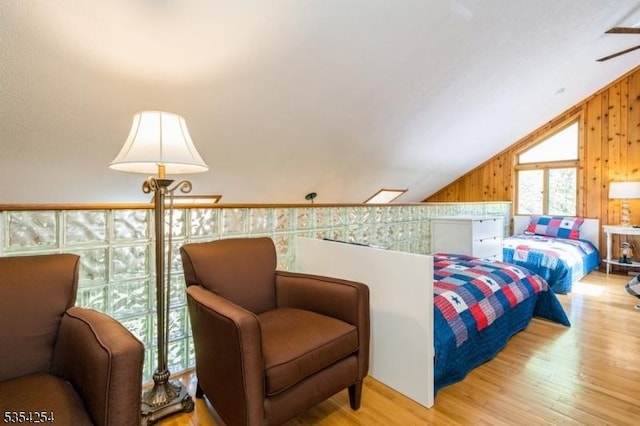 bedroom with wooden walls, vaulted ceiling, and wood finished floors