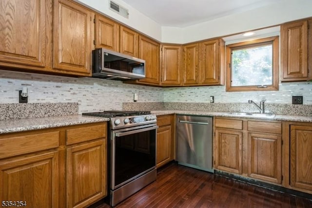 kitchen featuring brown cabinets, appliances with stainless steel finishes, a sink, and visible vents