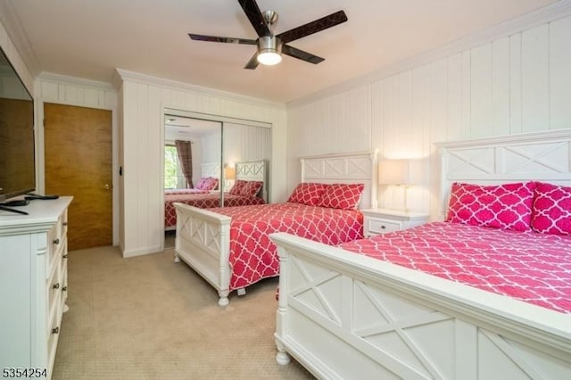 bedroom featuring crown molding, ceiling fan, light colored carpet, and a closet