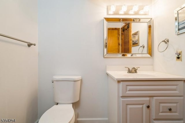 bathroom with toilet, baseboards, and vanity