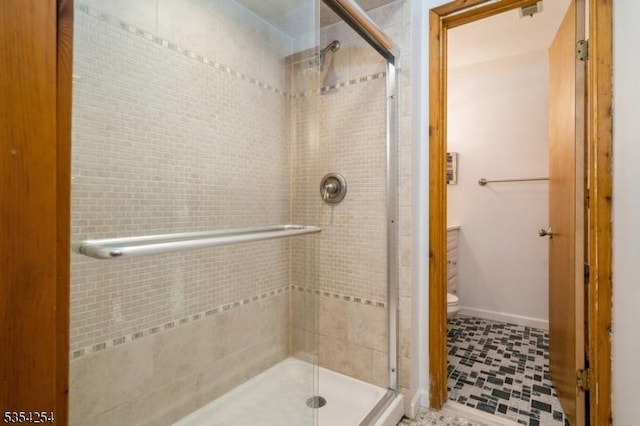full bathroom featuring toilet, baseboards, and a shower stall
