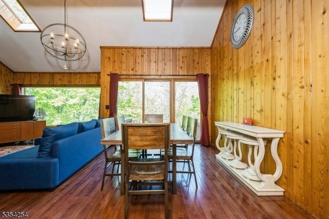 dining space featuring wood-type flooring, a chandelier, lofted ceiling, and wooden walls