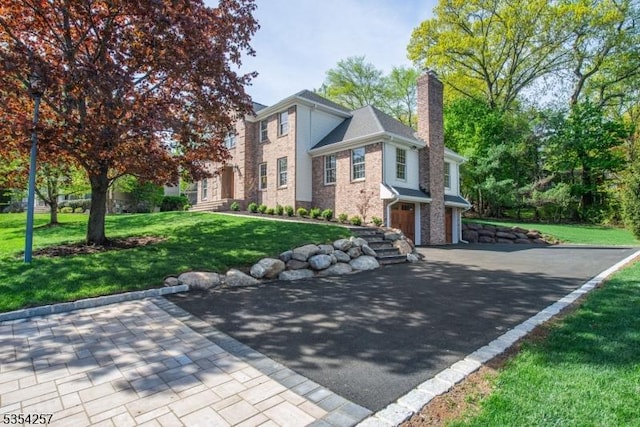 view of front of property with a chimney, an attached garage, driveway, and a front yard