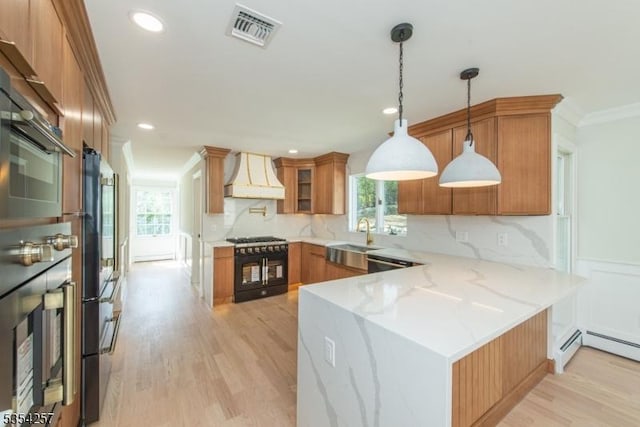 kitchen featuring visible vents, a peninsula, custom exhaust hood, black gas stove, and a sink