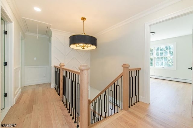 hallway featuring an upstairs landing, baseboard heating, attic access, and wood finished floors