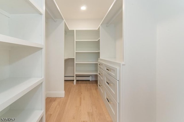 spacious closet with a baseboard radiator and light wood finished floors