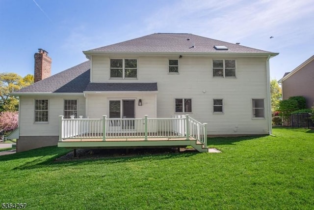 rear view of property with a lawn, a wooden deck, and a chimney