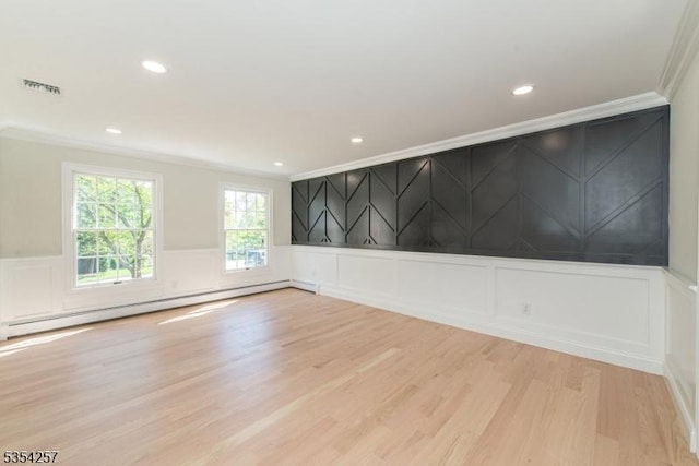 spare room with visible vents, crown molding, baseboard heating, a decorative wall, and light wood-style flooring