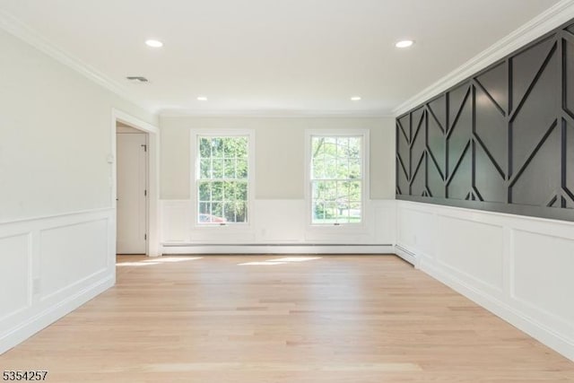 unfurnished room with ornamental molding, a baseboard heating unit, light wood finished floors, and a decorative wall