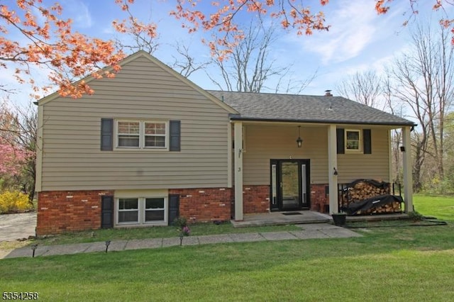 back of property featuring a lawn and brick siding