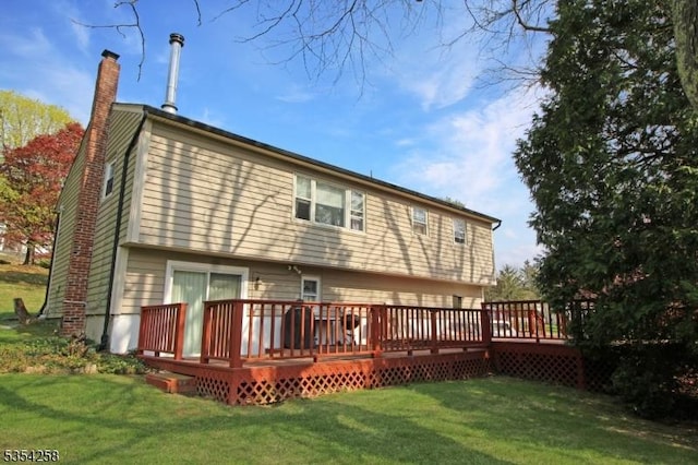 rear view of house featuring a lawn, a wooden deck, and a chimney