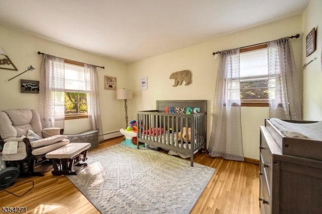 12 Fox Ledge Dr, Vernon Twp, NJ 07418 - bedroom featuring a nursery area, baseboard heating, and light wood-style flooring