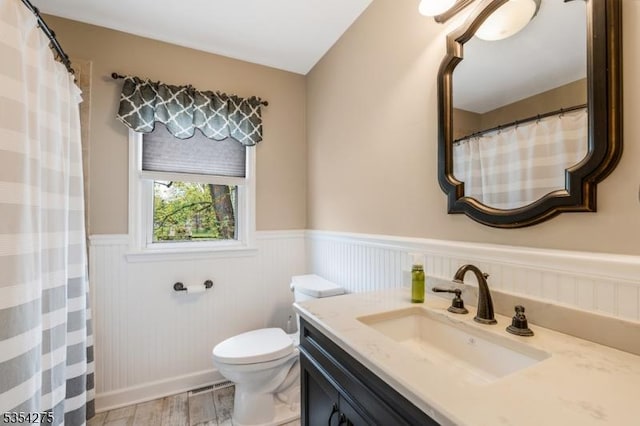 bathroom with vanity, a wainscoted wall, toilet, and wood finished floors