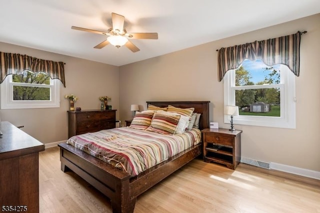 bedroom with baseboards, light wood-style flooring, ceiling fan, and visible vents