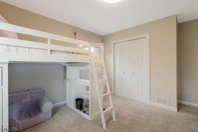 carpeted bedroom featuring baseboards, visible vents, and a closet