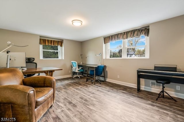 office space featuring baseboards, plenty of natural light, wood finished floors, and visible vents
