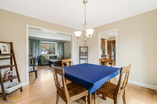 dining room with an inviting chandelier, baseboards, and light wood-style flooring