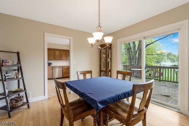 dining area featuring baseboards, an inviting chandelier, and light wood-style flooring