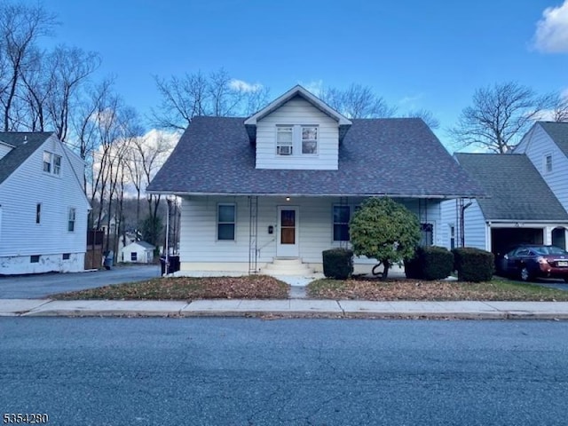 view of front of property featuring a garage, a shingled roof, and a porch